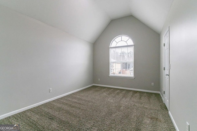 carpeted empty room with vaulted ceiling