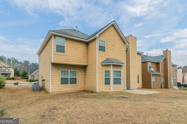 back of house with central AC unit, a patio area, and a lawn