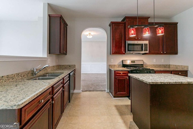 kitchen with sink, a center island, pendant lighting, stainless steel appliances, and light stone countertops