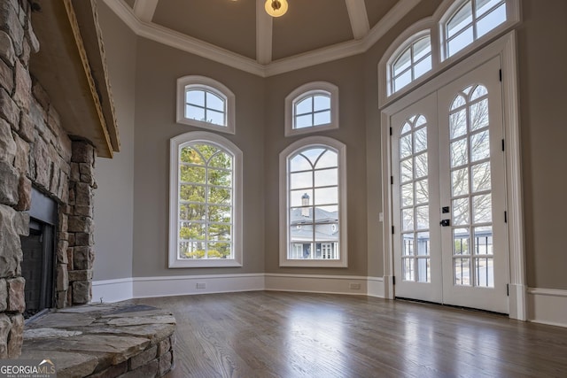 unfurnished living room with a stone fireplace, dark hardwood / wood-style floors, french doors, and a towering ceiling