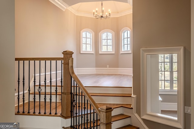 stairway featuring crown molding, a wealth of natural light, and a chandelier