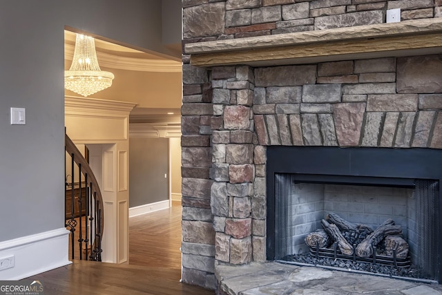 details with crown molding, hardwood / wood-style flooring, a fireplace, and a chandelier