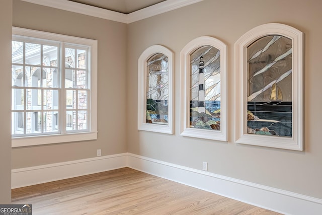 spare room with crown molding and light wood-type flooring