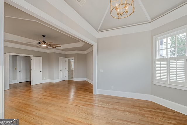 empty room featuring crown molding, a tray ceiling, and light wood-type flooring