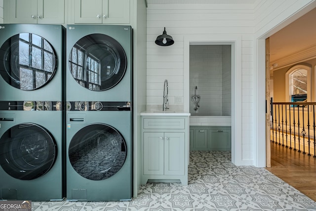 washroom featuring stacked washer and dryer, sink, and cabinets