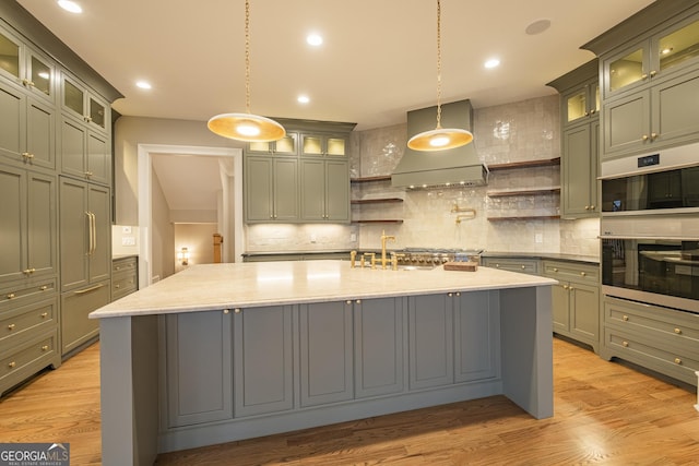 kitchen with premium range hood, stainless steel appliances, hanging light fixtures, and light wood-type flooring