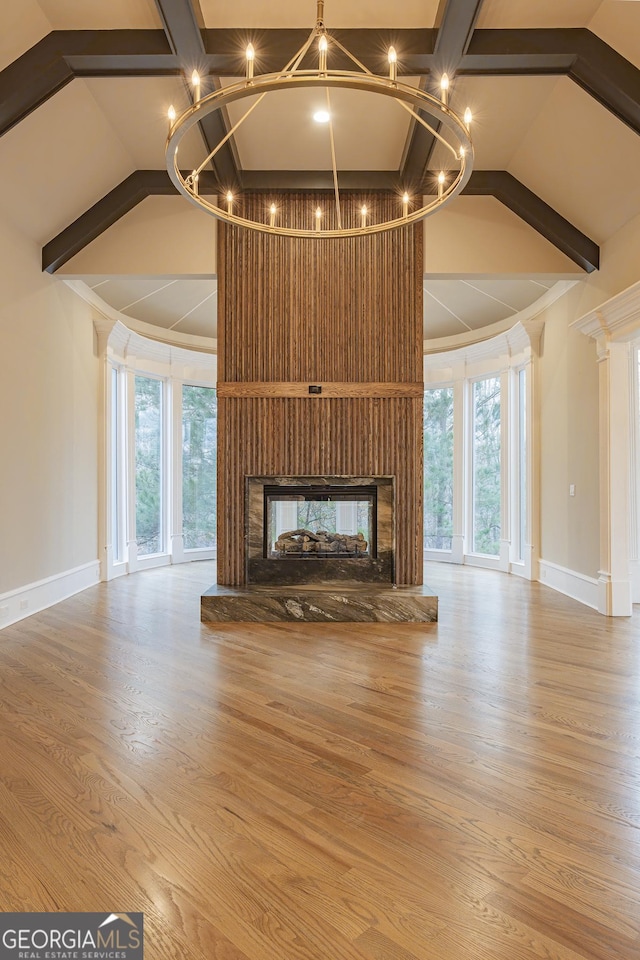 unfurnished living room featuring light hardwood / wood-style flooring, high vaulted ceiling, a chandelier, a multi sided fireplace, and beamed ceiling