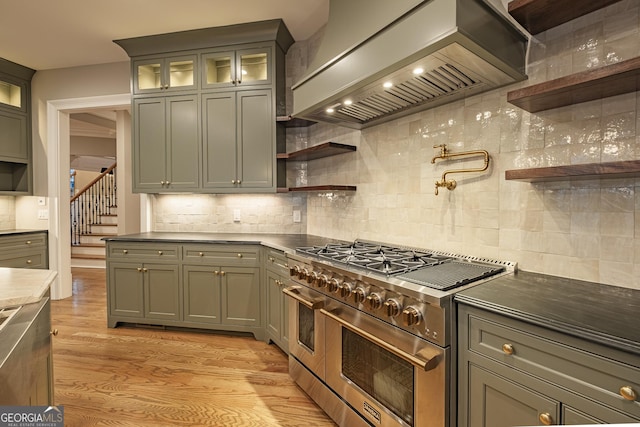 kitchen featuring range with two ovens, premium range hood, backsplash, and light hardwood / wood-style flooring