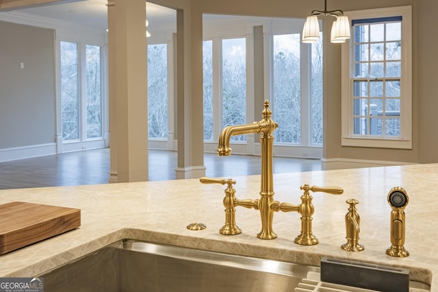 room details featuring sink, crown molding, an inviting chandelier, decorative light fixtures, and decorative columns