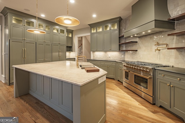 kitchen with hanging light fixtures, premium range hood, light hardwood / wood-style flooring, and double oven range