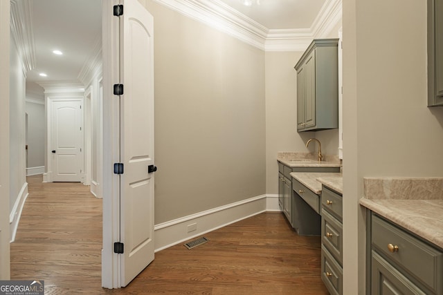 bathroom featuring sink, hardwood / wood-style flooring, and ornamental molding