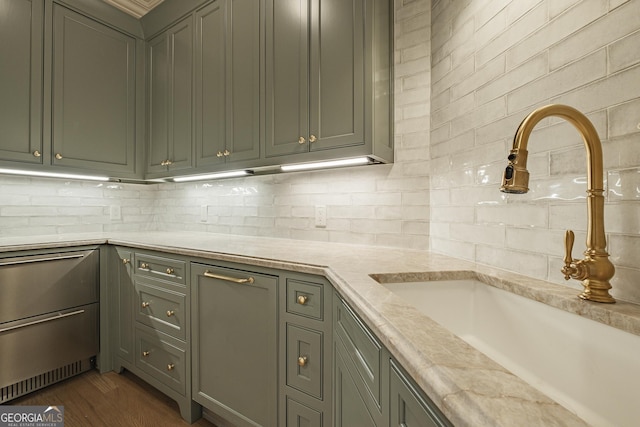 kitchen featuring light stone counters, sink, decorative backsplash, and dark hardwood / wood-style floors