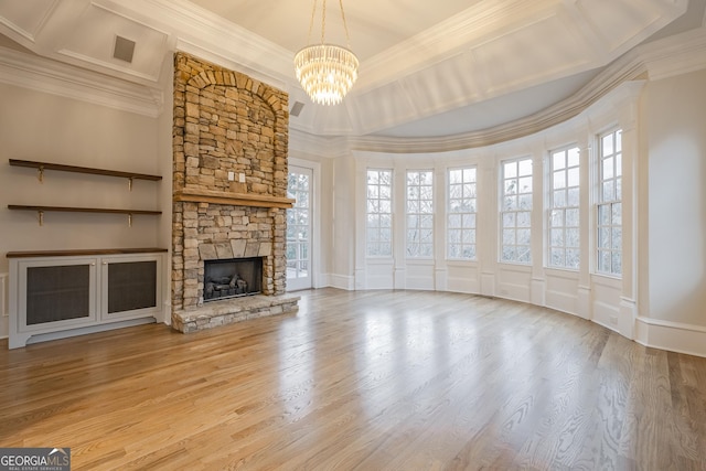 unfurnished living room with an inviting chandelier, a fireplace, wood-type flooring, and ornamental molding