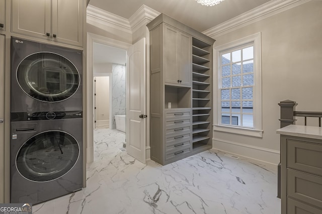 clothes washing area featuring cabinets, stacked washer / drying machine, and ornamental molding