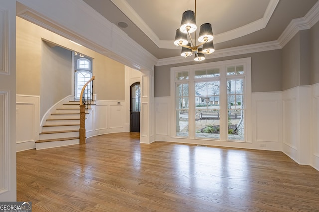 interior space featuring a raised ceiling, crown molding, hardwood / wood-style flooring, and a chandelier