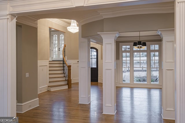 foyer with decorative columns, dark hardwood / wood-style flooring, a notable chandelier, crown molding, and french doors