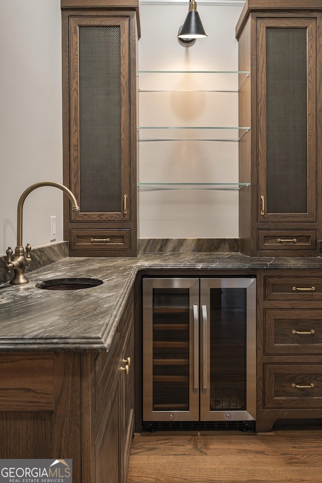 bar featuring wine cooler, dark brown cabinetry, dark hardwood / wood-style floors, and sink