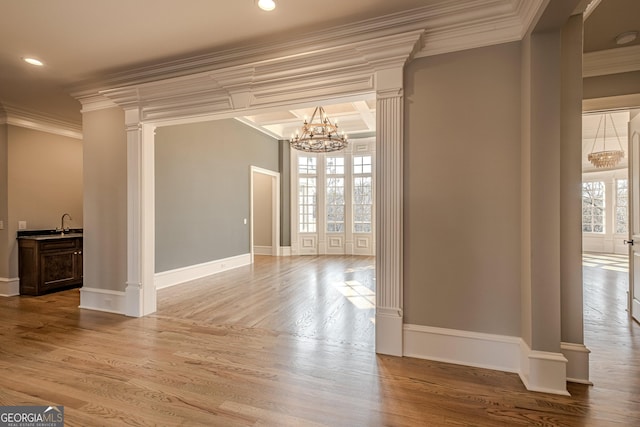 interior space with sink, crown molding, decorative columns, a chandelier, and light wood-type flooring