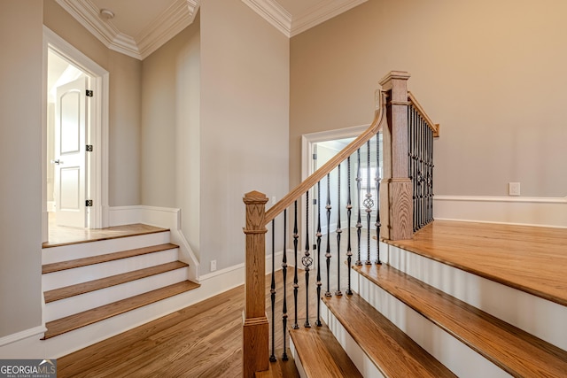 stairway featuring ornamental molding and wood-type flooring