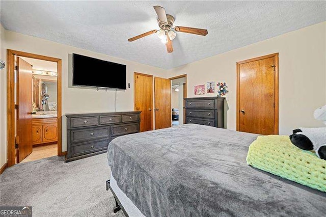 carpeted bedroom featuring connected bathroom, a textured ceiling, and ceiling fan