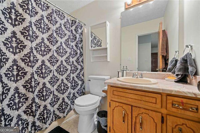 bathroom featuring vanity, a textured ceiling, tile patterned floors, and toilet