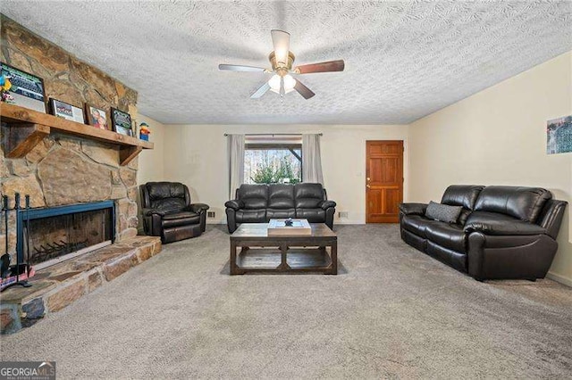 carpeted living room with a stone fireplace, a textured ceiling, and ceiling fan