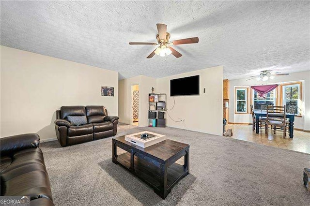 living room with ceiling fan, carpet floors, and a textured ceiling