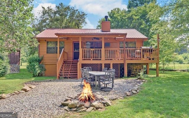 rear view of house featuring a fire pit, a wooden deck, stairs, a chimney, and a yard