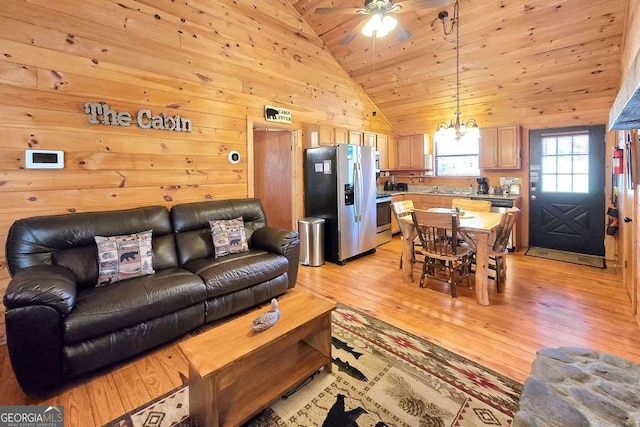 living area with ceiling fan with notable chandelier, wood walls, light wood finished floors, lofted ceiling, and wood ceiling