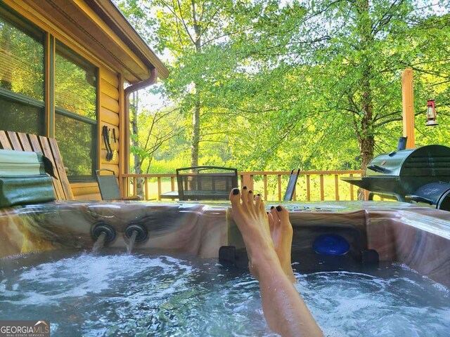 wooden terrace with a hot tub and area for grilling