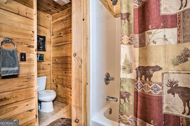 bathroom featuring toilet, shower / bath combination, tile patterned flooring, and wood walls