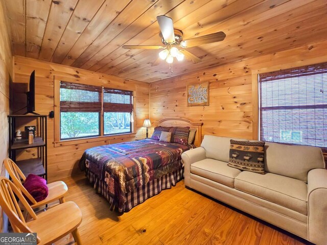 bedroom featuring wood walls, wooden ceiling, ceiling fan, and light hardwood / wood-style flooring