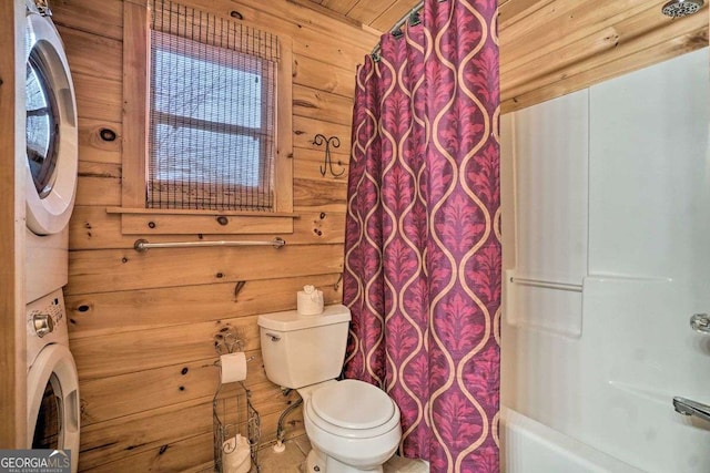 bathroom with shower / bathtub combination with curtain, wood walls, toilet, and stacked washing maching and dryer