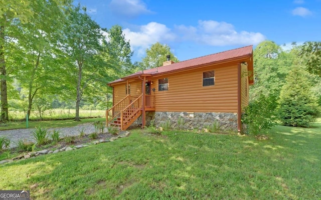 back of property with faux log siding, stairs, a chimney, metal roof, and a yard