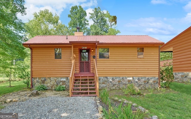 view of front facade with crawl space, faux log siding, a chimney, and metal roof