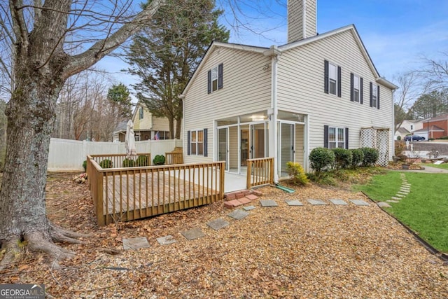 rear view of property with a deck and a lawn