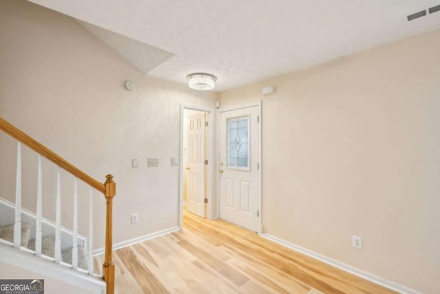 entryway with visible vents, light wood-style flooring, baseboards, and stairs