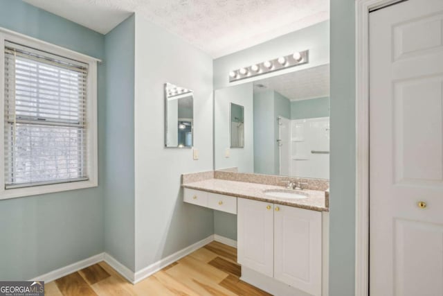 bathroom featuring a shower, vanity, a textured ceiling, wood finished floors, and baseboards