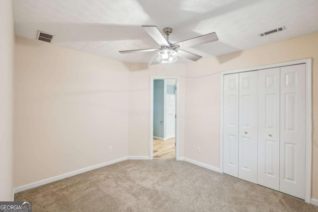 unfurnished bedroom with light colored carpet, a closet, and ceiling fan