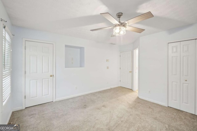 unfurnished bedroom featuring a closet, light colored carpet, ceiling fan, and baseboards