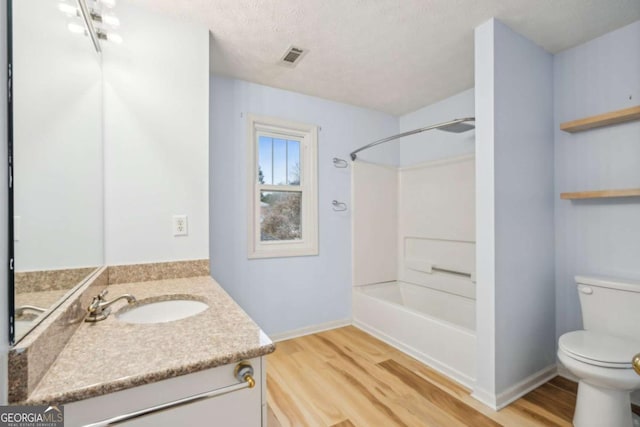 full bath featuring bathing tub / shower combination, toilet, wood finished floors, a textured ceiling, and vanity