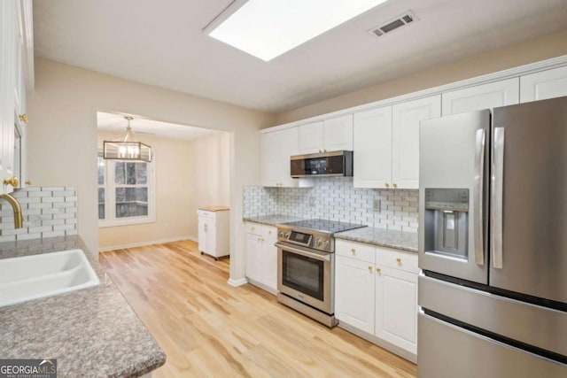 kitchen with stainless steel appliances, sink, decorative backsplash, and white cabinets