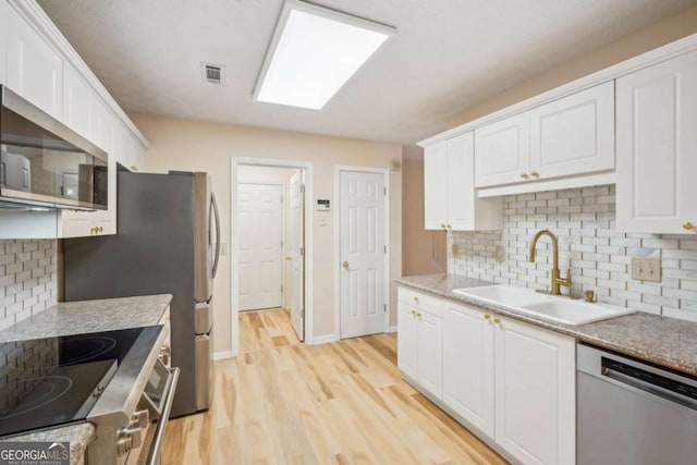 kitchen with appliances with stainless steel finishes, sink, and white cabinets