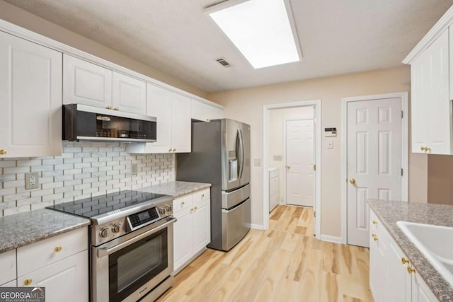 kitchen with sink, light wood-type flooring, white cabinets, and appliances with stainless steel finishes