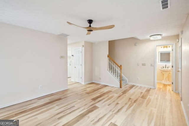 empty room featuring visible vents, ceiling fan, stairway, and light wood finished floors