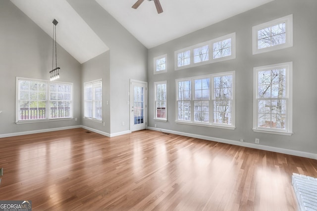 unfurnished living room with wood-type flooring, high vaulted ceiling, and ceiling fan