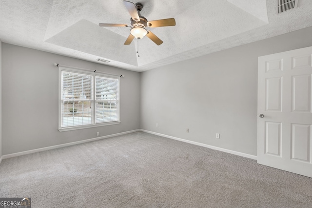 carpeted spare room featuring ceiling fan, a raised ceiling, and a textured ceiling