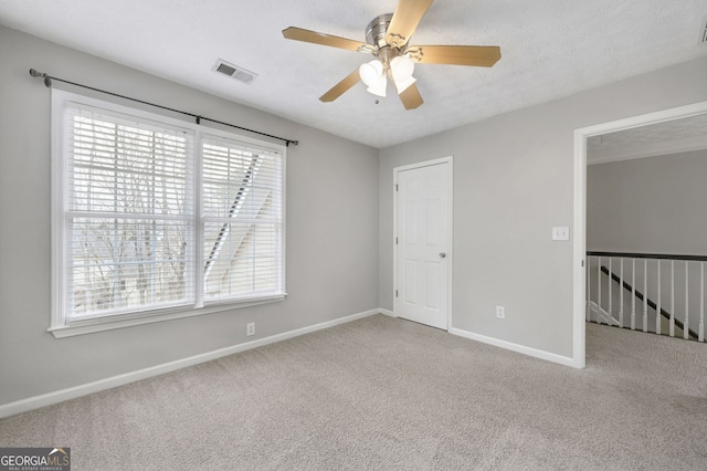 spare room featuring carpet, a healthy amount of sunlight, and ceiling fan