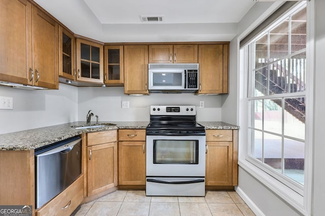 kitchen featuring light tile patterned flooring, appliances with stainless steel finishes, light stone countertops, and sink