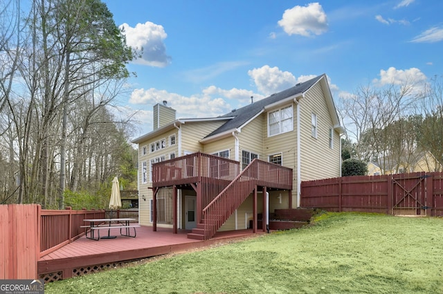 back of property featuring a wooden deck and a lawn